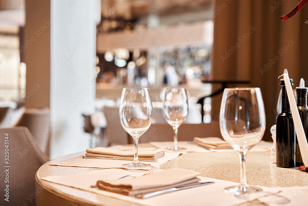 Wine glasses in the foreground. The chairs and table for guests, served with cutlery and crockery Wine glasses in the foreground. The chairs and table for guests, served with cutlery and crockery