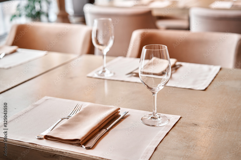 Wine glasses in the foreground. The chairs and table for guests, served with cutlery and crockery Wine glasses in the foreground. The chairs and table for guests, served with cutlery and crockery