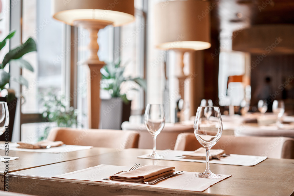 Wine glasses in the foreground. The chairs and table for guests, served with cutlery and crockery