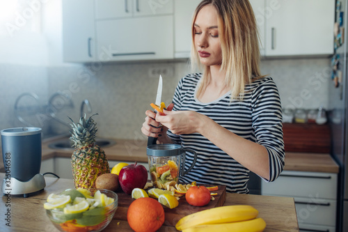 Young woman preparing smoothie. Young woman preparing healthy fruit drink at the kitchen.