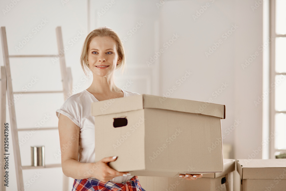 A beautiful single young woman unpacking boxes and moving into a new home A beautiful single young woman unpacking boxes and moving into a new home