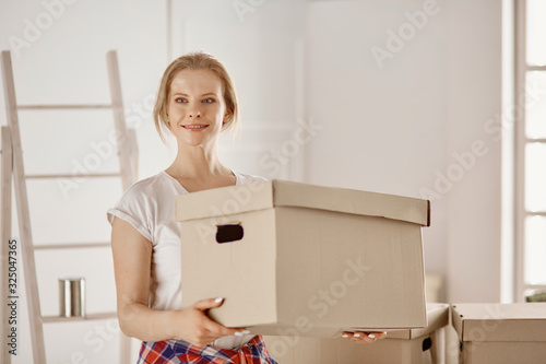 A beautiful single young woman unpacking boxes and moving into a new home © lenetsnikolai