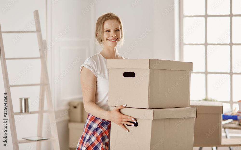 A beautiful single young woman unpacking boxes and moving into a new home A beautiful single young woman unpacking boxes and moving into a new home
