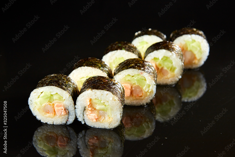 Traditional sushi roll with salmon, cream cheese, shrimp and cucumber on black stone. Japanese food Traditional sushi roll with salmon, cream cheese, shrimp and cucumber on black stone. Japanese food