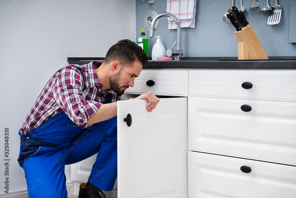 Man In Overall Repairing Cabinet