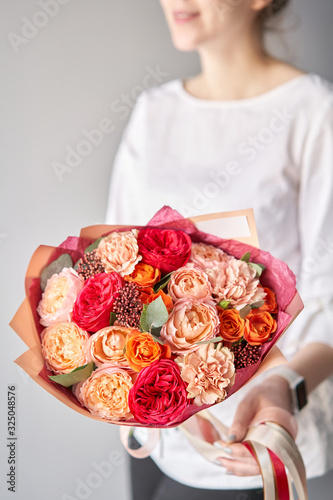 Beautiful bouquet of mixed flowers in womans hands. the work of the florist at a flower shop. Delivery fresh cut flower. European floral shop.