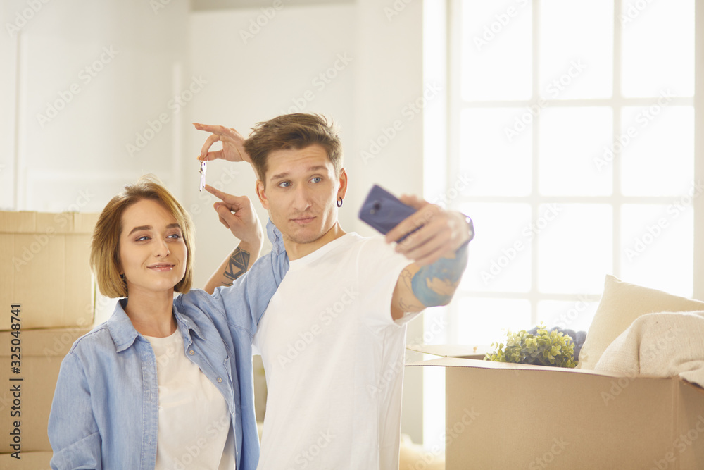Obraz premium Happy smiling young couple showing a pair of keys of their new house