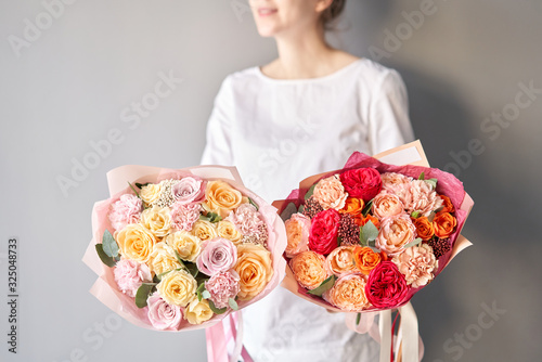 Two Beautiful bouquets of mixed flowers in womans hands. the work of the florist at a flower shop. Delivery fresh cut flower. European floral shop.