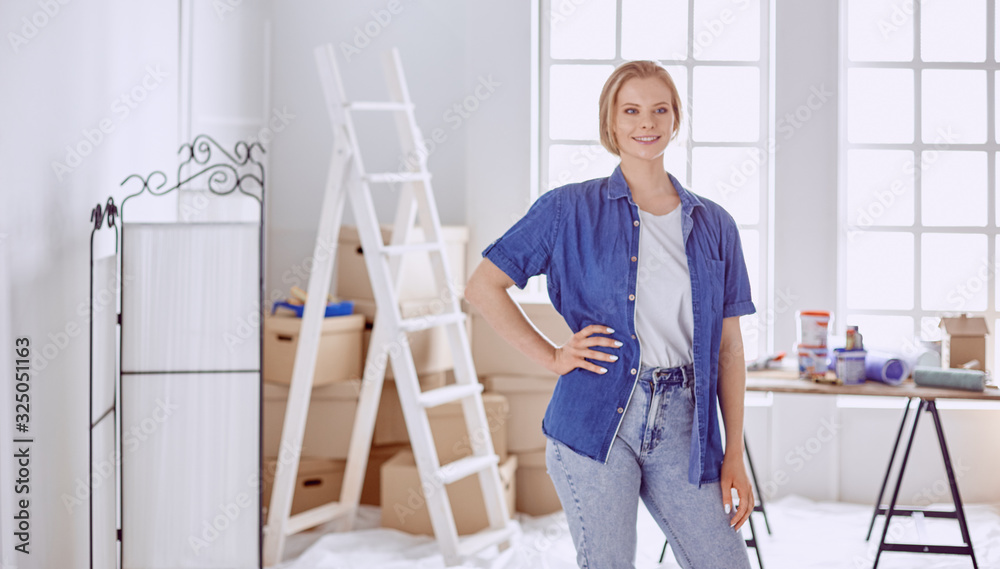 Beautiful young woman on a white wooden stepladder. Ready to repair the room. Women housework concept