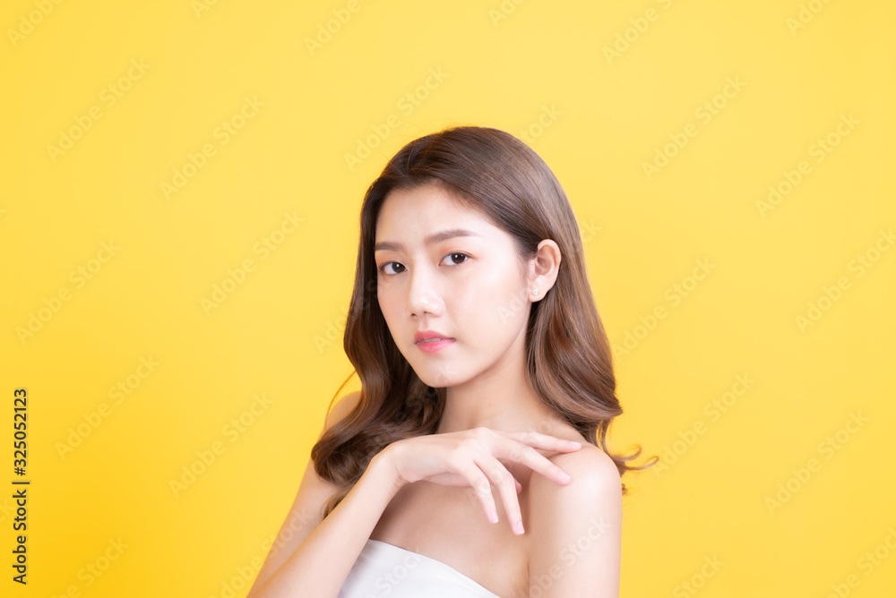 skin care concept. porprait posing asia beauty woman hand touch face and shoulder with yellow background studio shooting skin care concept. porprait posing asia beauty woman hand touch face and shoulder with yellow background studio shooting