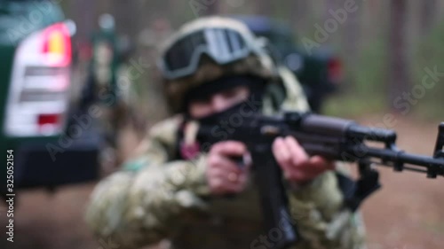 Soldier tracks target, front view. Soldier prepares to shoot a machine gun. Barrel of a machine gun close-up. The fighting squad was ambushed. Concept of war, army and military. Commando squad. photo