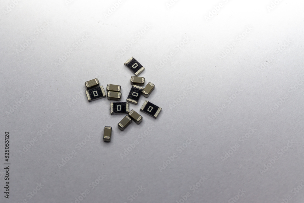 Abstract close-up scattered 0603 SMT MLCC capacitors, resistors electronics components white background random pattern Abstract close-up scattered 0603 SMT MLCC capacitors, resistors electronics components white background random pattern
