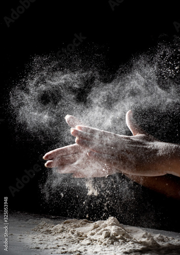 woman chef hand clap with splash of white flour and black background