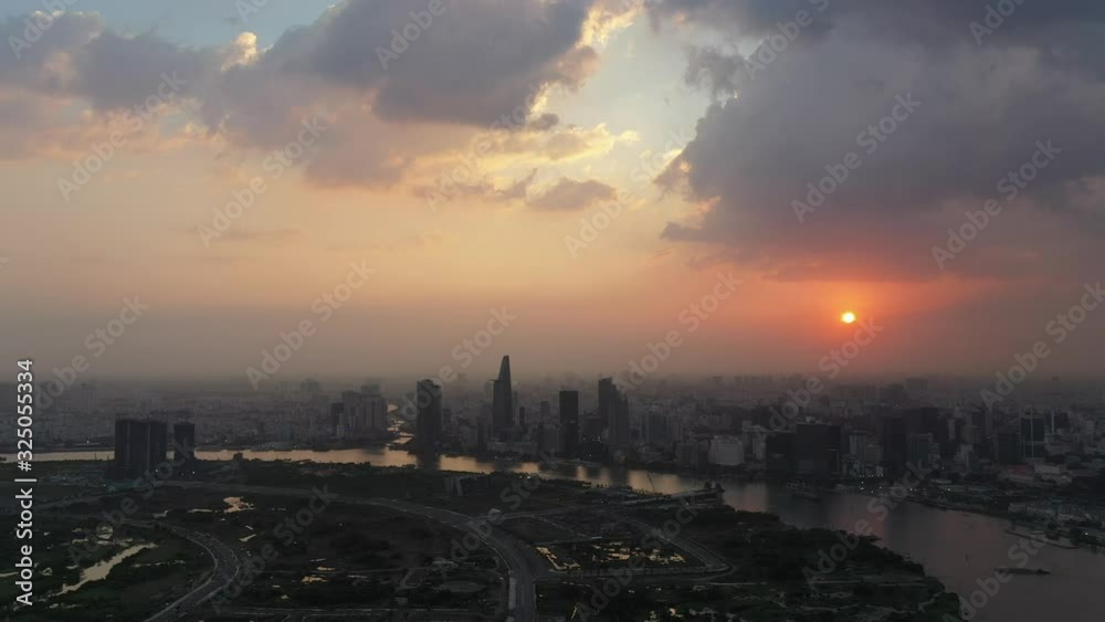 Dramatic aerial view of Saigon river and Ho Chi Minh City skyline at sunset with beautiful stormy and brightly colored clouds in the sky. Camera away from City center Dramatic aerial view of Saigon river and Ho Chi Minh City skyline at sunset with beautiful stormy and brightly colored clouds in the sky. Camera away from City center
