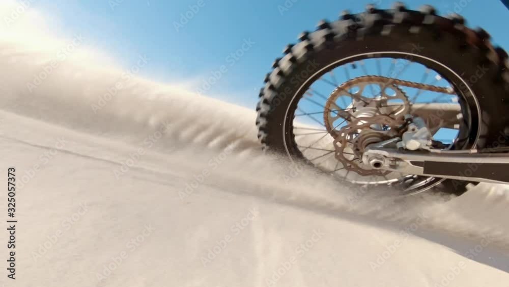 Skilled motocross rider drives on the sand dune. Dirt biker off roading on sand dunes in desert.