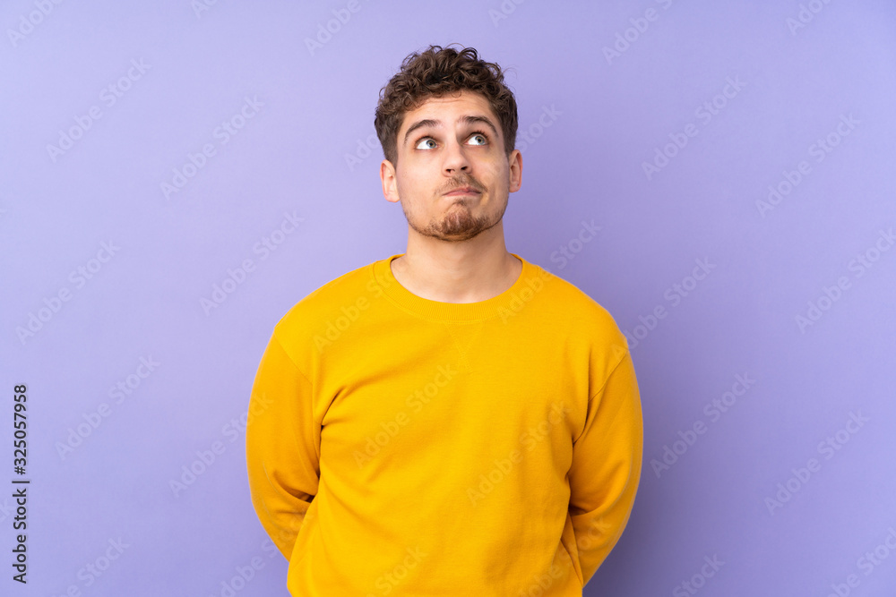 Caucasian man isolated on purple background and looking up Caucasian man isolated on purple background and looking up