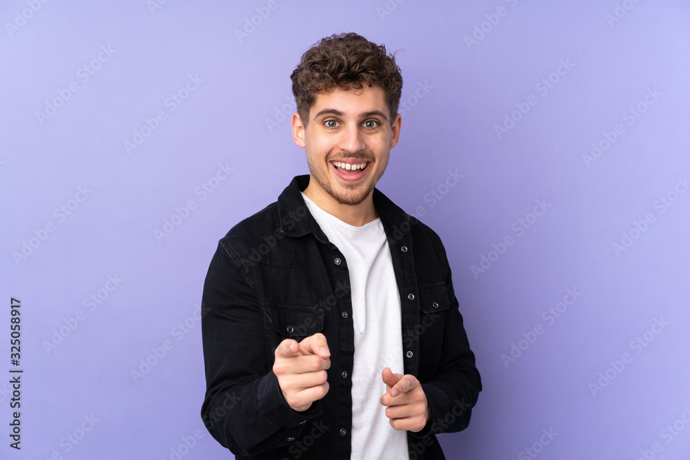 Caucasian man isolated on purple background surprised and pointing front Caucasian man isolated on purple background surprised and pointing front