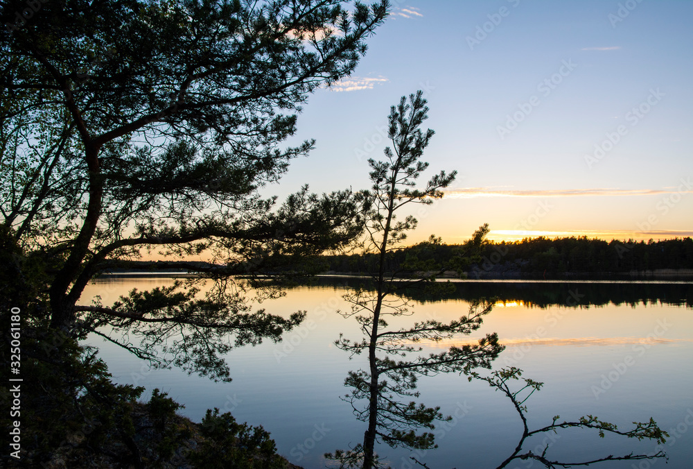 Beautiful evening coastal view, silhouettes of pine trees and reflection in the sea on the background, Korpo island, Finland