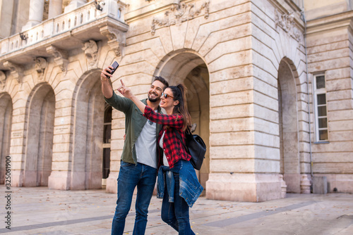 A happy couple taking a selfie in while sightseeing ion a European city
