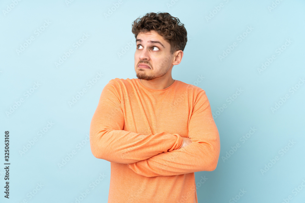 Caucasian man isolated on blue background making doubts gesture while lifting the shoulders Caucasian man isolated on blue background making doubts gesture while lifting the shoulders