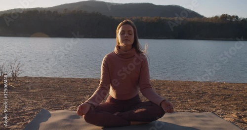 A woman sits and meditates on the shoreline photo