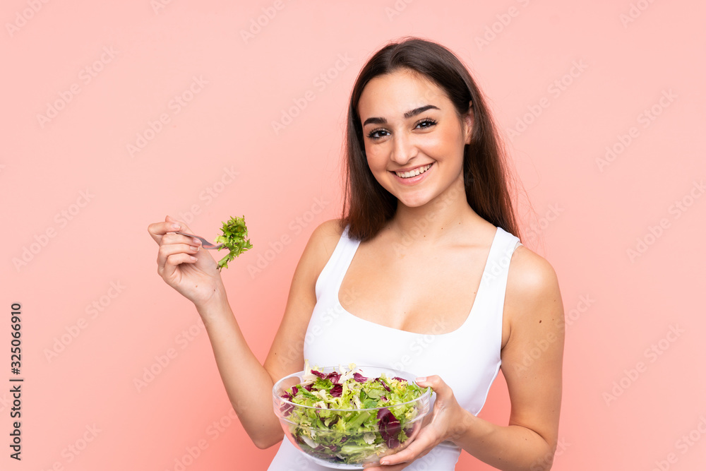 Young caucasian woman holding a salad isolated on pink background Young caucasian woman holding a salad isolated on pink background