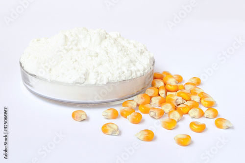 Petri dish with corn starch and yellow kernels on a white background. Closeup of tapioca starch or powder flour on a white background. Powder starch and corn grains on a white background.