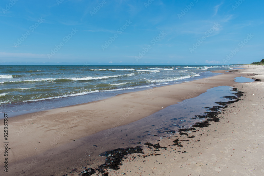 Steep sand shore beach with clouds and blue sky Steep sand shore beach with clouds and blue sky