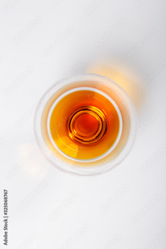A glass of cognac stands on a white background. The view from the top A glass of cognac stands on a white background. The view from the top