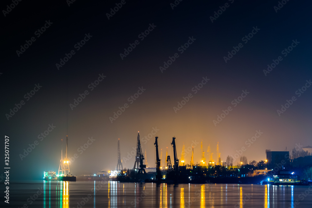 shipyard at night with reflection on water