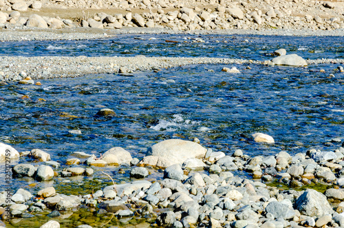 small river flowing through nature, stone bottom of the stream, clear water flows into the water reservoir