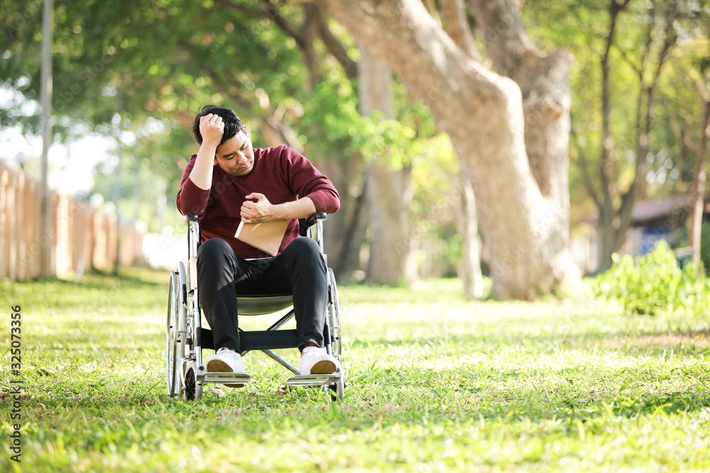 Asian Young Man sitting on the wheelchair in the park hospital Asian Young Man sitting on the wheelchair in the park hospital