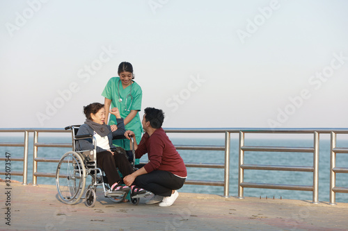 Asian senior woman sitting on the wheelchair with woman in doctor uniform in the park hospital