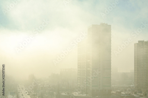 Built new high-rise building in dense morning fog with penetrating rays of the sun.