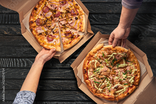 Overhead view of hands taking pizza from cardboard box