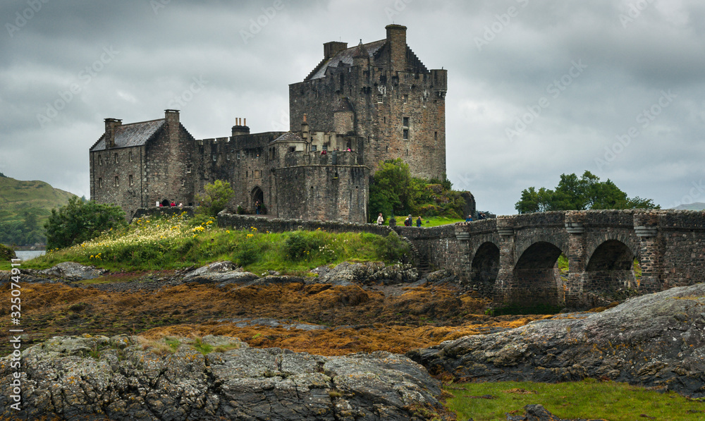 Landscape with the old castle and fortress of Eilean Donan on the shores of Lake Duich in Scotland, with very cloudy sky.