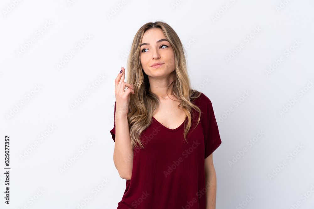 Young woman over isolated white background with fingers crossing and wishing the best Young woman over isolated white background with fingers crossing and wishing the best