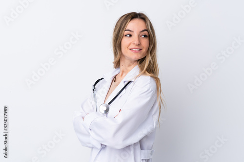 Young woman over isolated white background wearing a doctor gown and with arms crossed