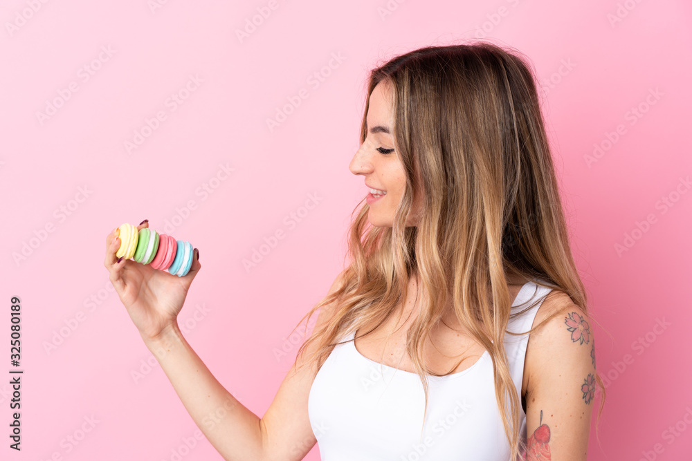 Young woman with macarons over isolated pink background with happy expression Young woman with macarons over isolated pink background with happy expression
