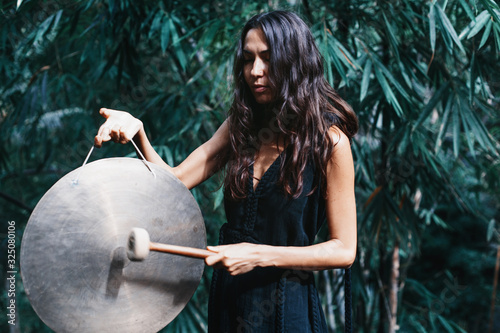 Young beautiful woman holding and playing gong outdoor
