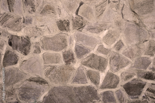 The texture of a gray wall consisting of cobblestones. Architecture