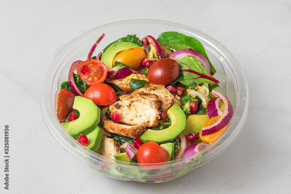 Healthy chicken salad with avocado, tomatoes and pomegranate in plastic package for take away or food delivery Healthy chicken salad with avocado, tomatoes and pomegranate in plastic package for take away or food delivery