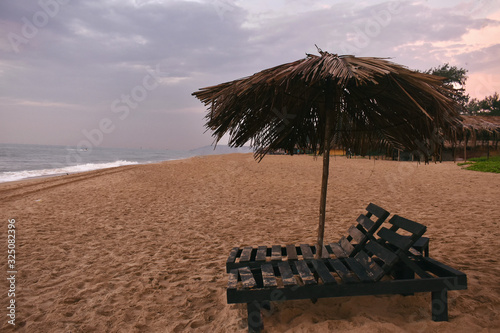 wooden sitting area in beach of goa with eco-friendly umbrella