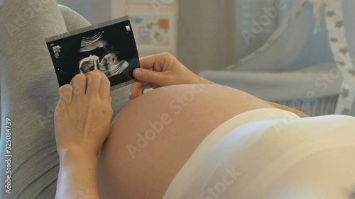 Surrogate mother, third-party reproduction. Surrogacy, pregnancy birth and baby. Pregnant woman looks at the ultrasound scan. Surrogate mother who changed her mind must hand baby