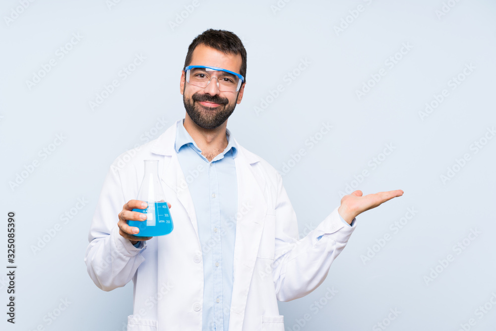 Young scientific holding laboratory flask over isolated background holding copyspace imaginary on the palm to insert an ad Young scientific holding laboratory flask over isolated background holding copyspace imaginary on the palm to insert an ad