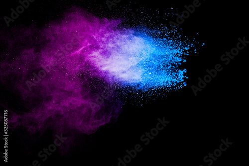 Purple blue color powder explosion cloud on black background.Closeup of purple blue dust particles splash.