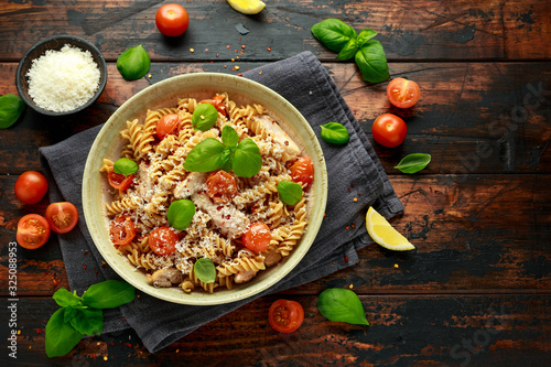Healthy Chicken, fusilli pasta with tomatoes, basil and parmesan cheese. on wooden table. photo
