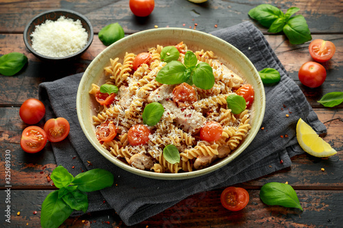 Healthy Chicken, fusilli pasta with tomatoes, basil and parmesan cheese. on wooden table.