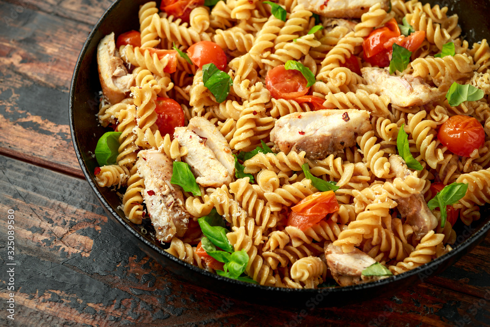 Healthy Chicken, fusilli pasta with tomatoes, basil and parmesan cheese in iron pan. Healthy Chicken, fusilli pasta with tomatoes, basil and parmesan cheese in iron pan.