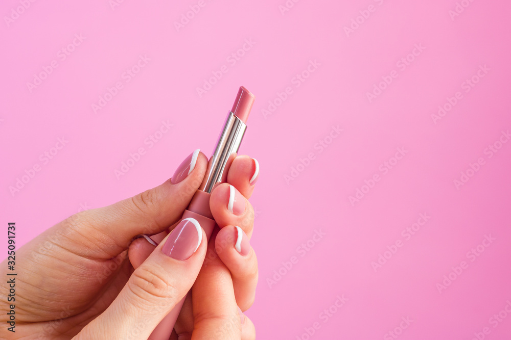 woman hand holding lipstick on pink background woman hand holding lipstick on pink background